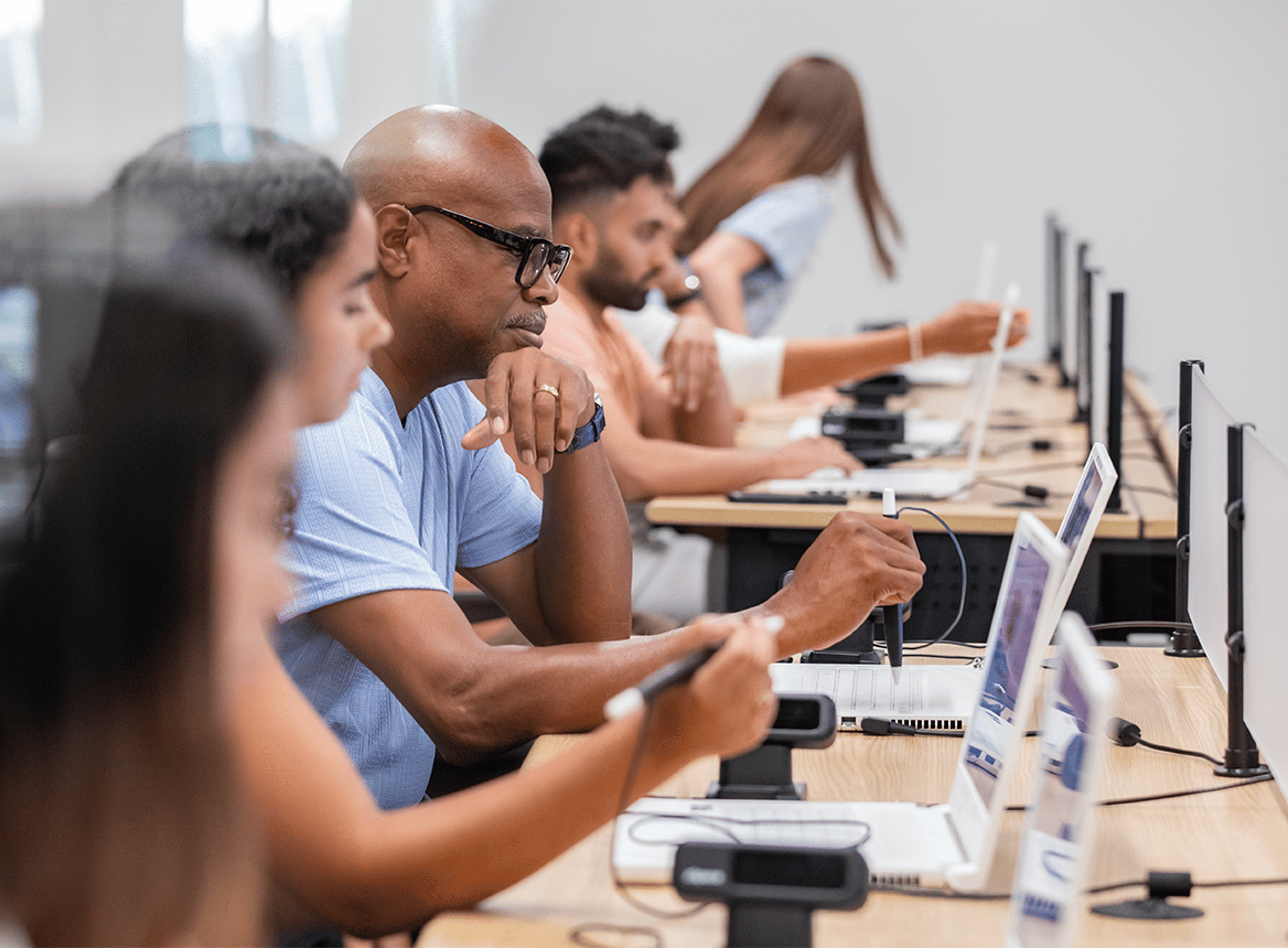 Row of Students at Desks Working at Laptops