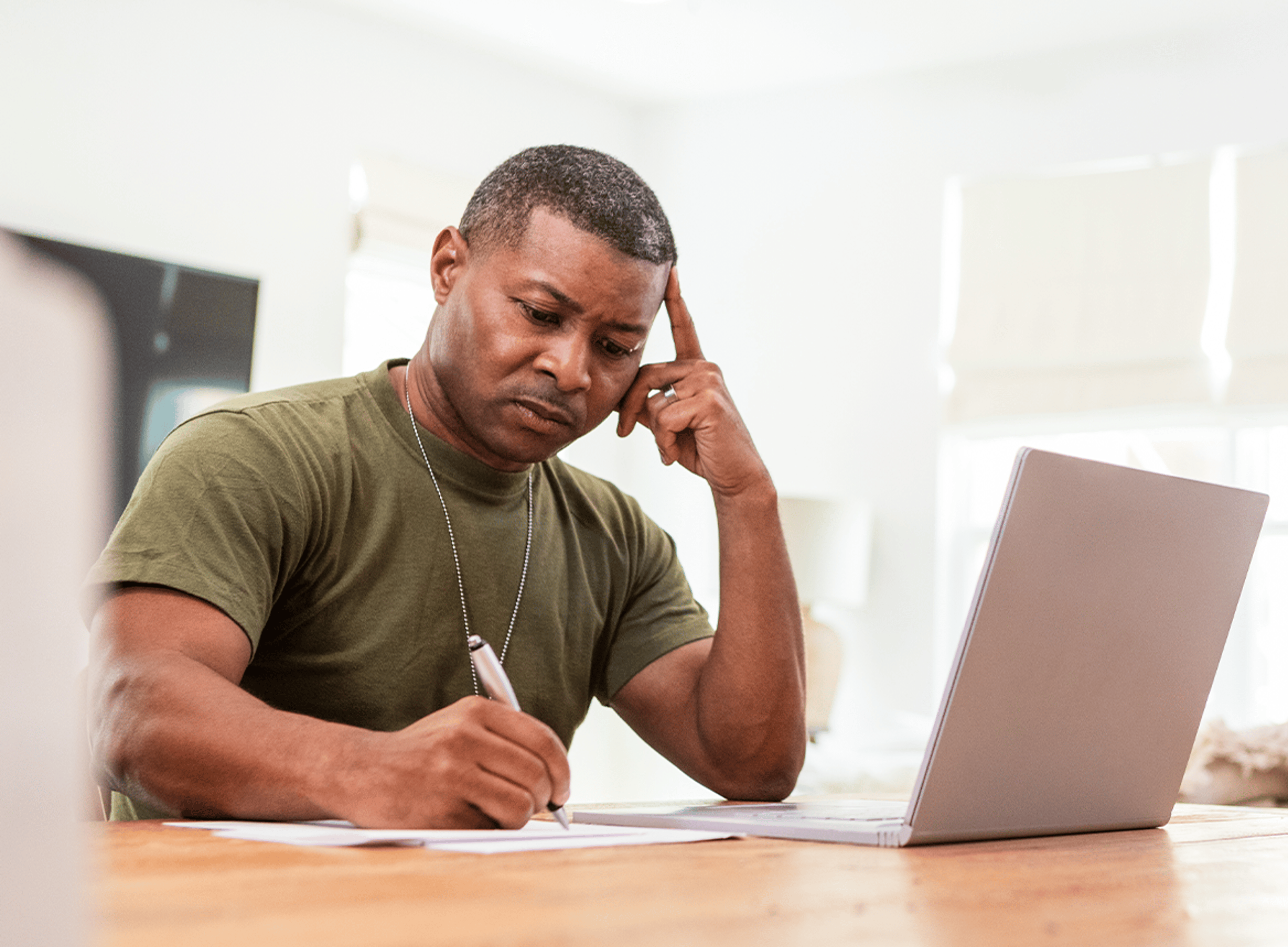 Veteran taking notes whilst using a laptop