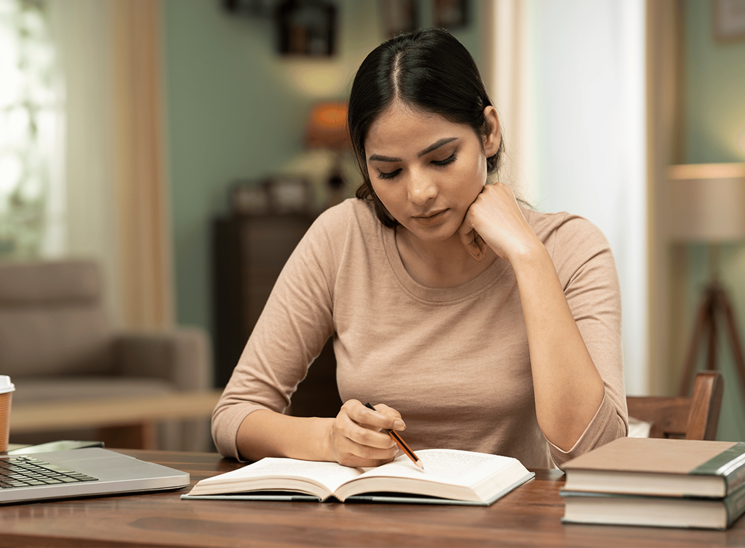Woman studying at desk with notepad and pen
