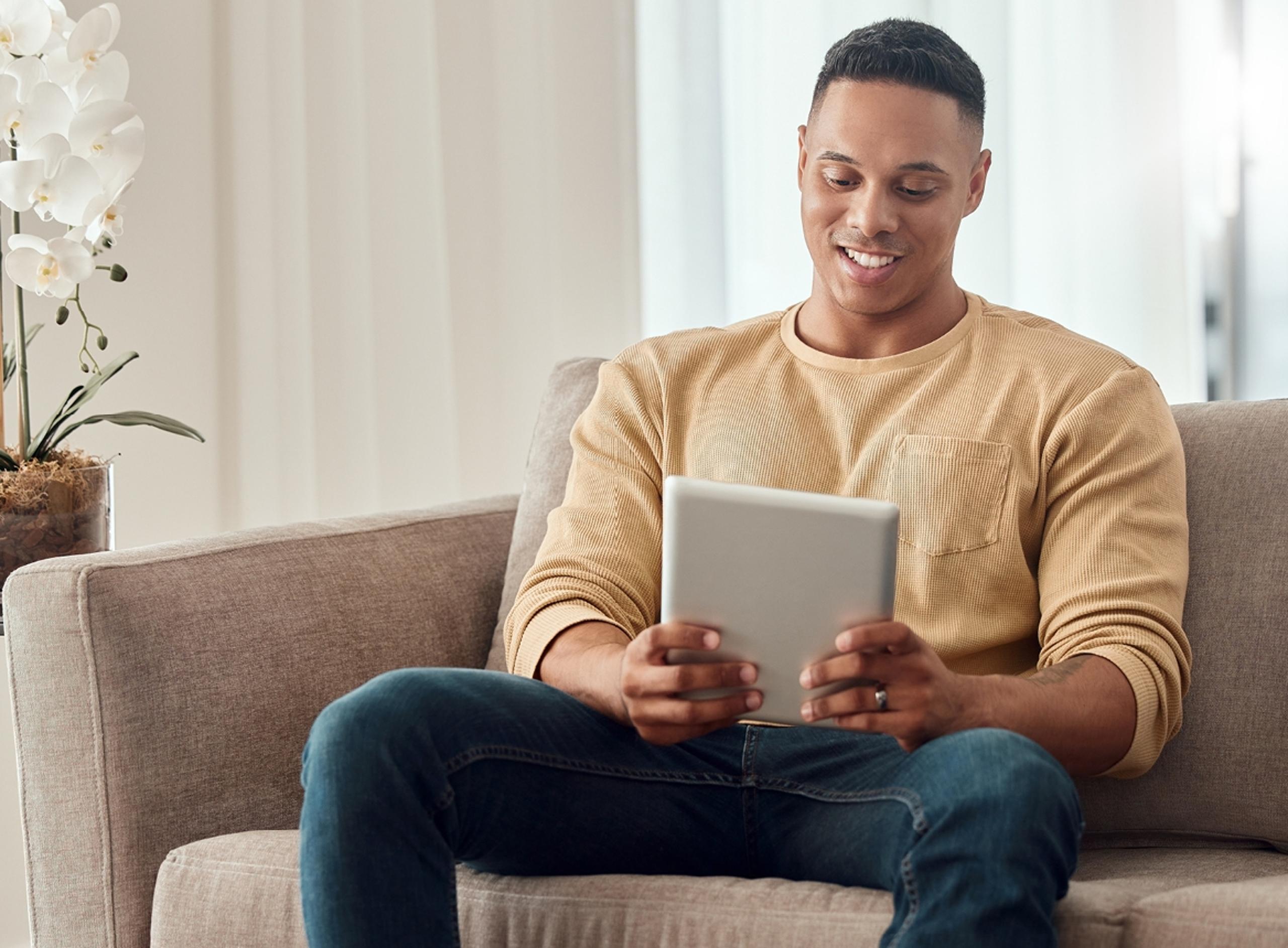 Smiling Man at Home Looking at Tablet