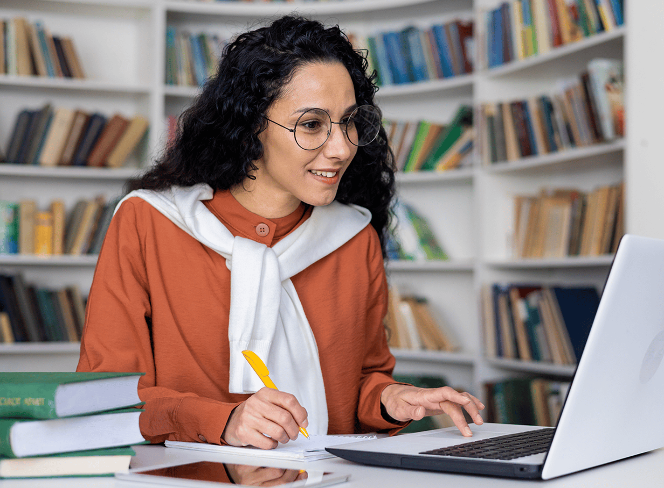Woman studying from home writing on notepad with laptop