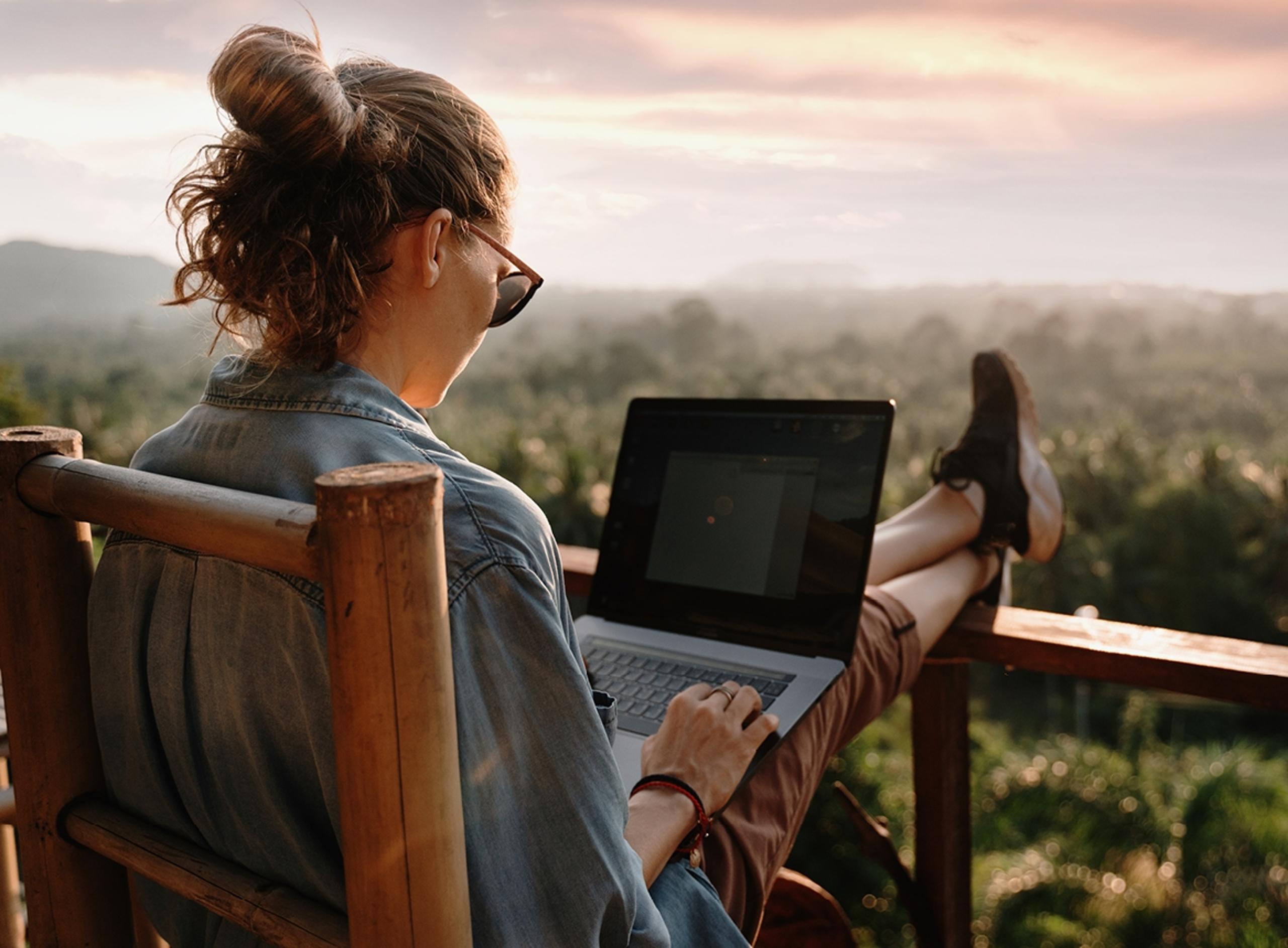 Woman With Her Feet on Railing and Laptop on Her Lap