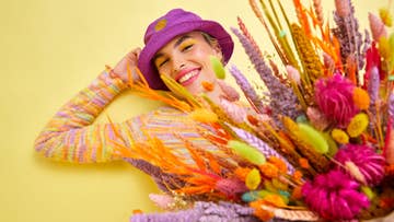 women in purple hat holding dry flowers