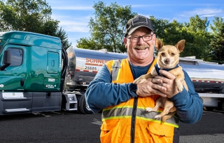A Tanker owner-owner stands in front of his truck with his chihuahua 
