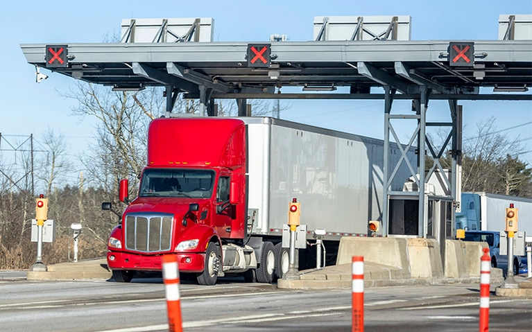 A semi-truck driving through a toll.