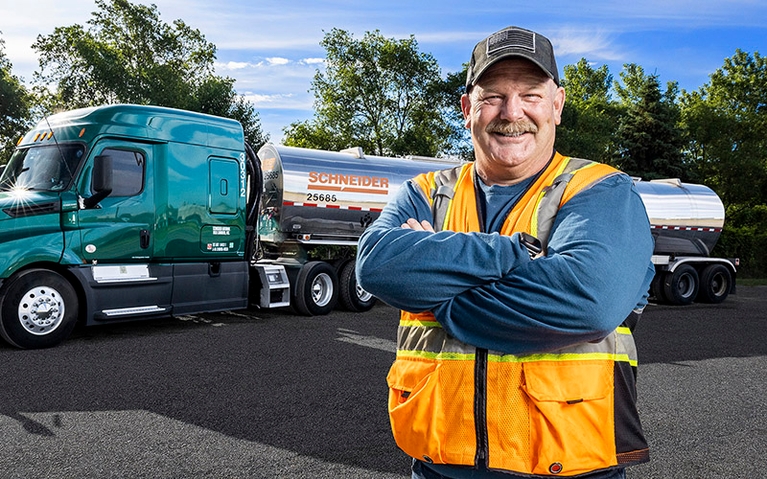 A man standing in front of a Schneider tanker truck.