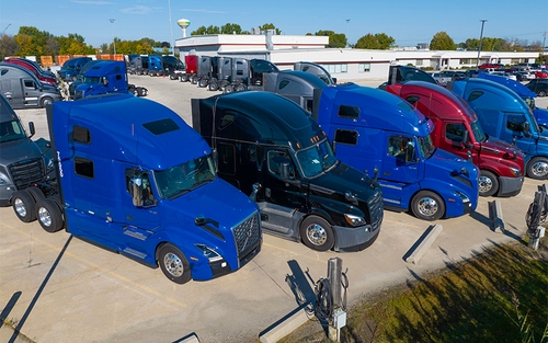 Semi-trucks lined up in a parking lot.