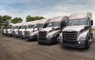 A row of multiple used semi trucks available for purchase.
