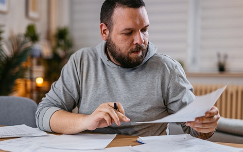 A man sitting at a table sorting through paperwork.