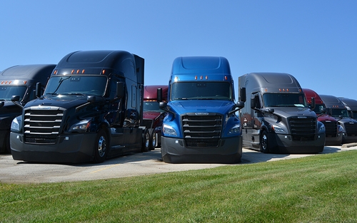 Semi-trucks lined up in a parking lot.