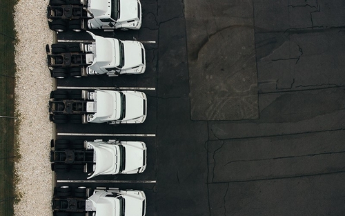 A birds eye view of five white semi-trucks parked in a row.