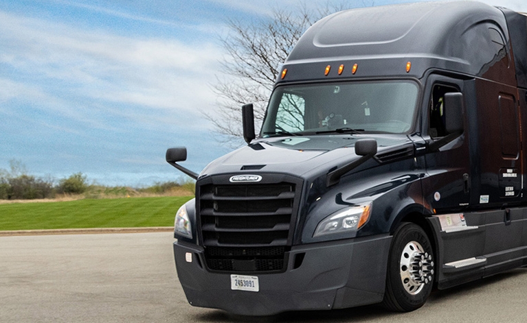 A black Freightliner Cascadia semi-truck parked in a lot.