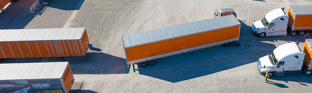 An aerial view of an owner-operator backing up his truck and trailer between two trailers during Schneider's orientation