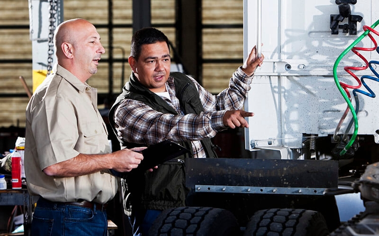 An owner-operator discussing his truck's maintenance needs with a technician