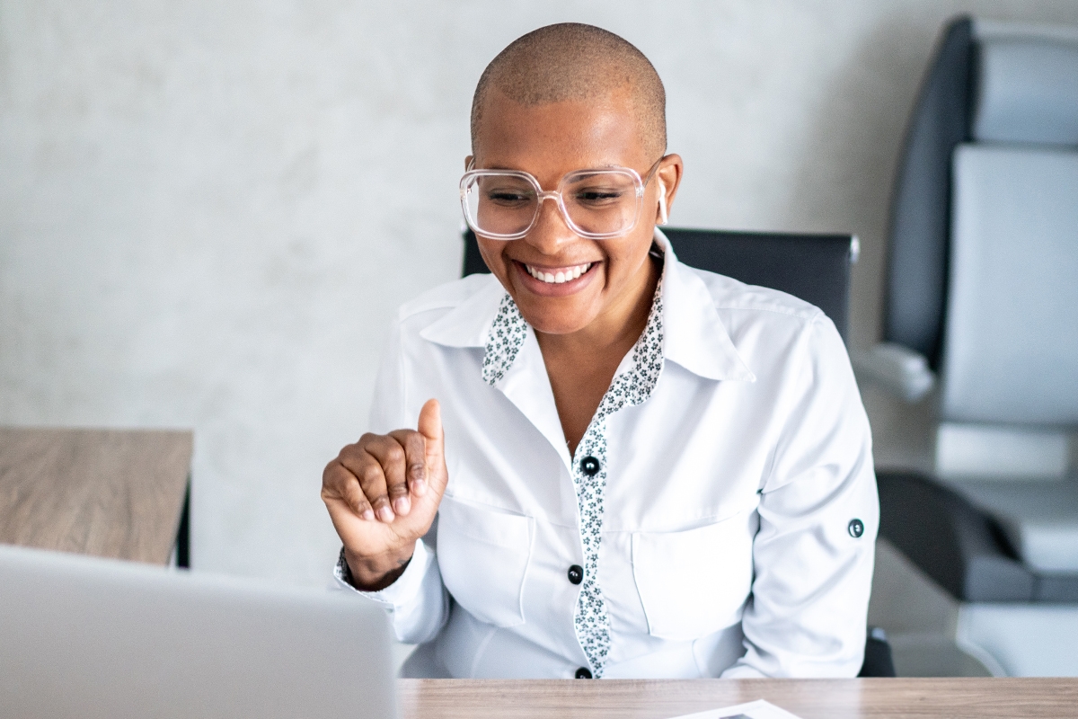 Eye doctor in front of a laptop waving at the screen
