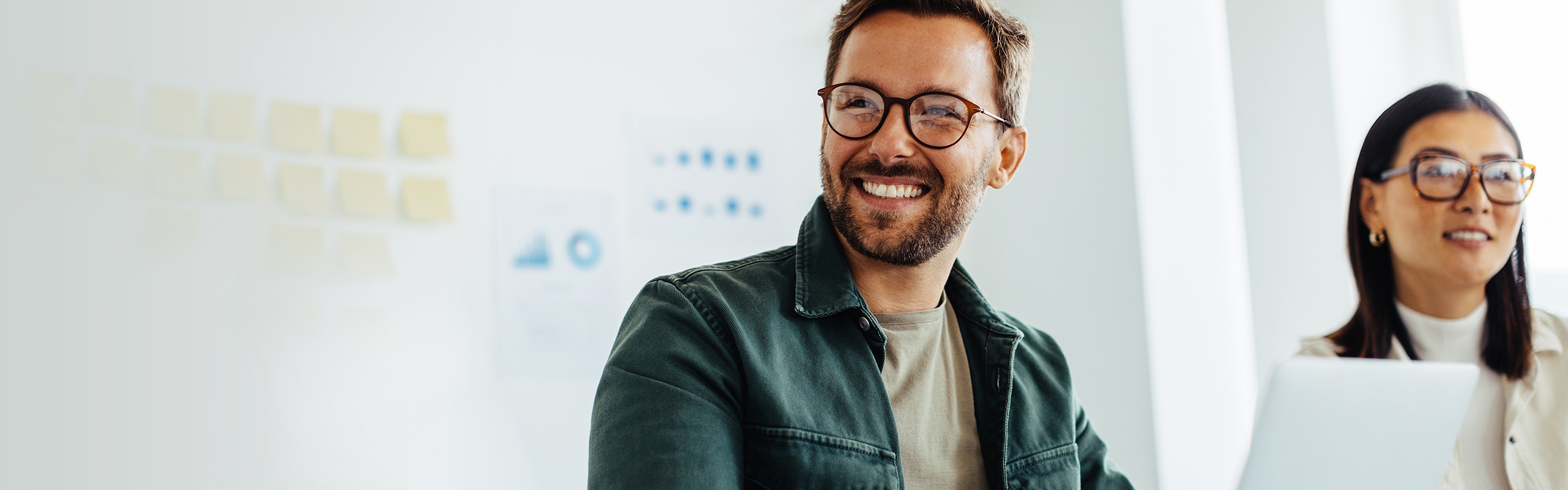 Man with glasses smiling in front of a laptop