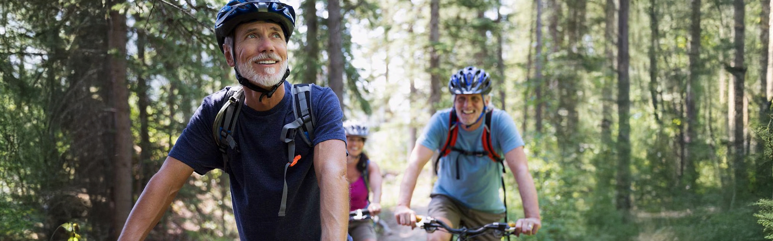 Three people riding a bike through the woods
