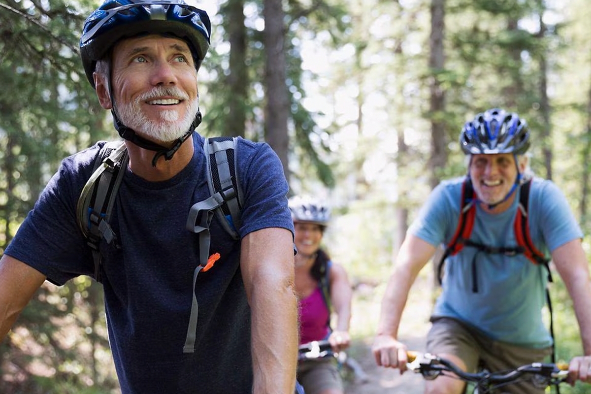 Three people riding a bike through the woods
