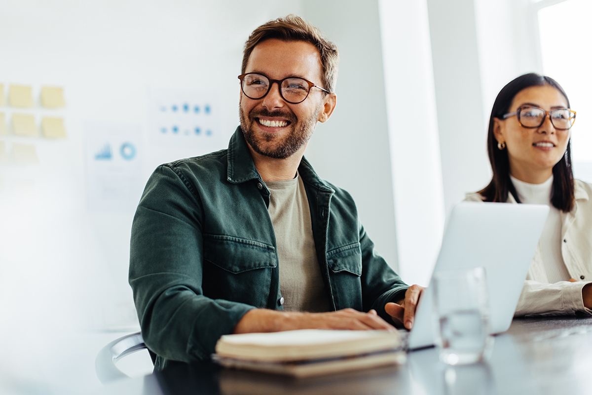 Man with glasses smiling in front of a laptop