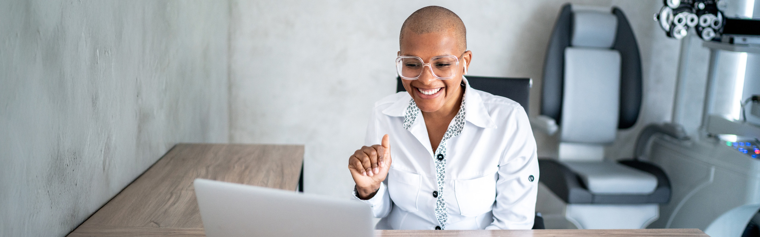 Eye doctor in front of a laptop waving at the screen