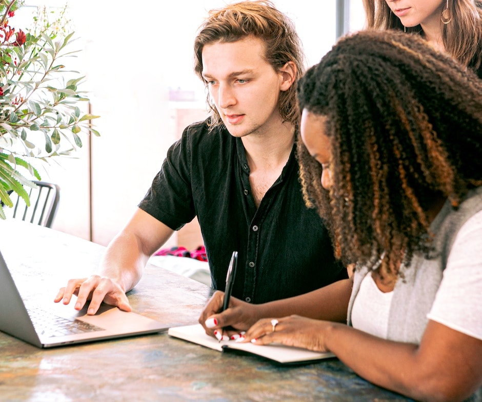 people sitting on a table looking at laptop analyzing and taking notes