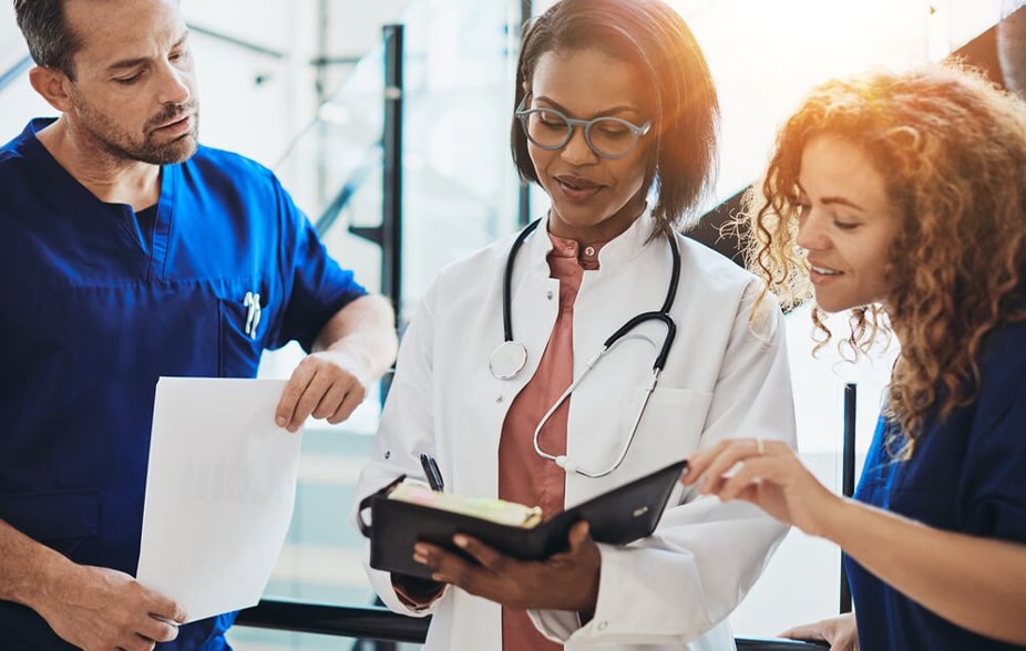 três profissionais médicos discutindo o trabalho