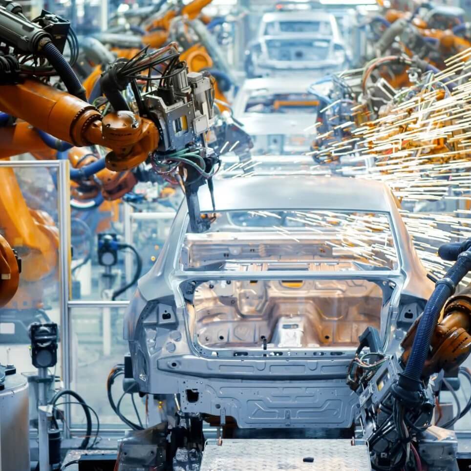 Automated robotic arms welding a car frame on an automotive production line.