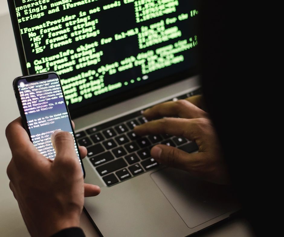 person using cell phone and laptop