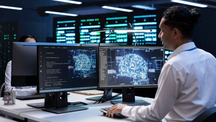 homem trabalhando em uma mesa com dois monitores