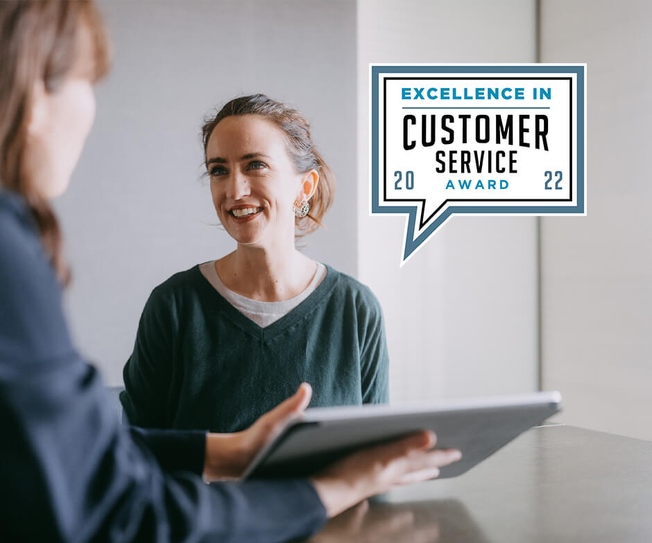 Dos mujeres hablando sobre trabajar con el logotipo de Customer Service Award de Business Intelligence Group.