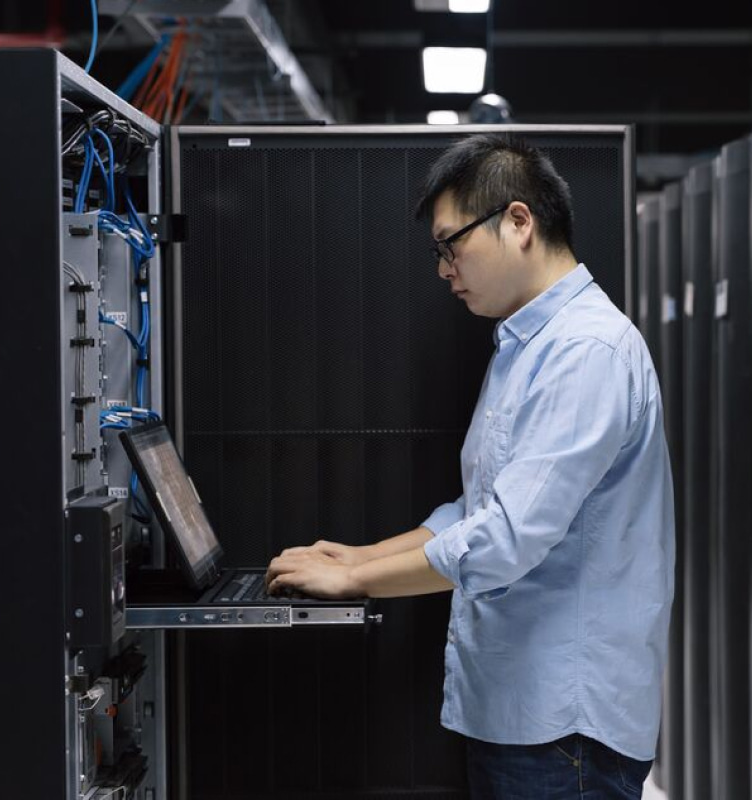 Man working on laptop with a server open in front of him