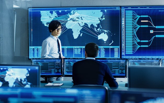 Two people in an office with a lot of computers and screens