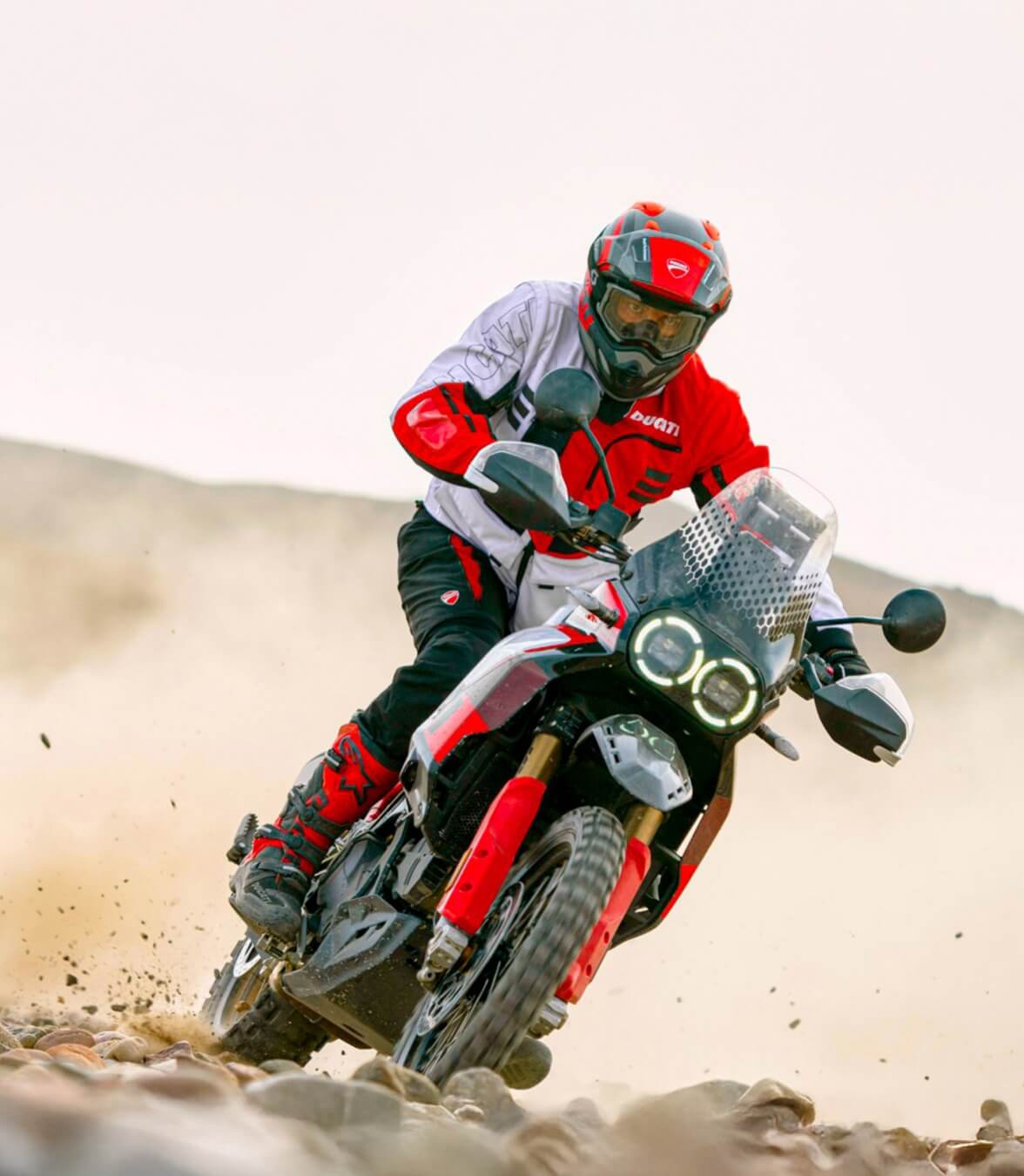 A motocross rider wearing Ducati Explorer apparel speeds through dirt terrain