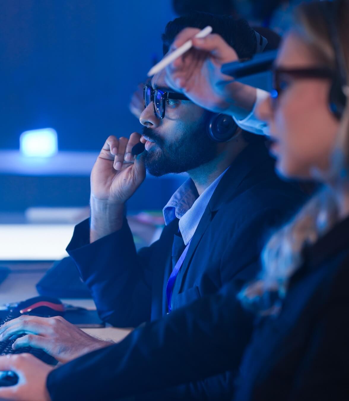 Team members working at computer stations in a technology operations environment.