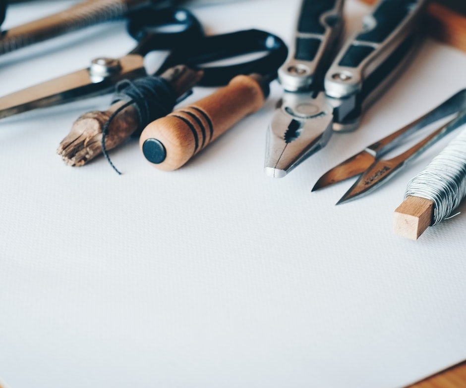 tailor tools like scissors, thread, dividers and compass on white paper