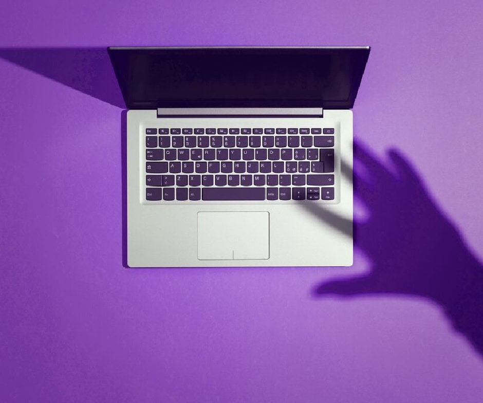 person hand shadow on mac keyboard with purple background