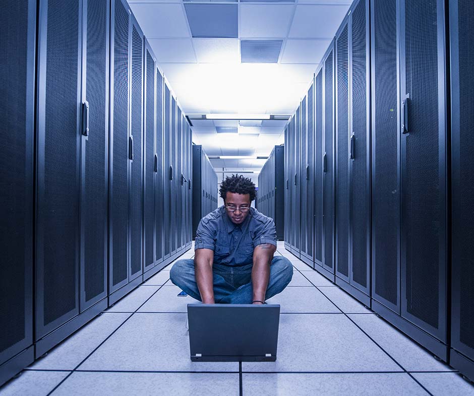 person working with laptop in datacenter
