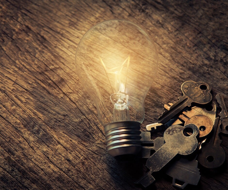 Lightbulb next to keys on a wooden table