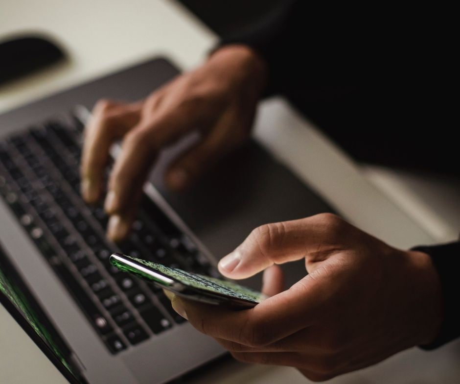 Person working on phone and laptop