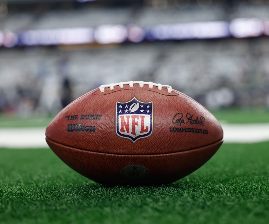 Gros plan sur un ballon de football américain posé sur le terrain avec le logo NFL bien visible.