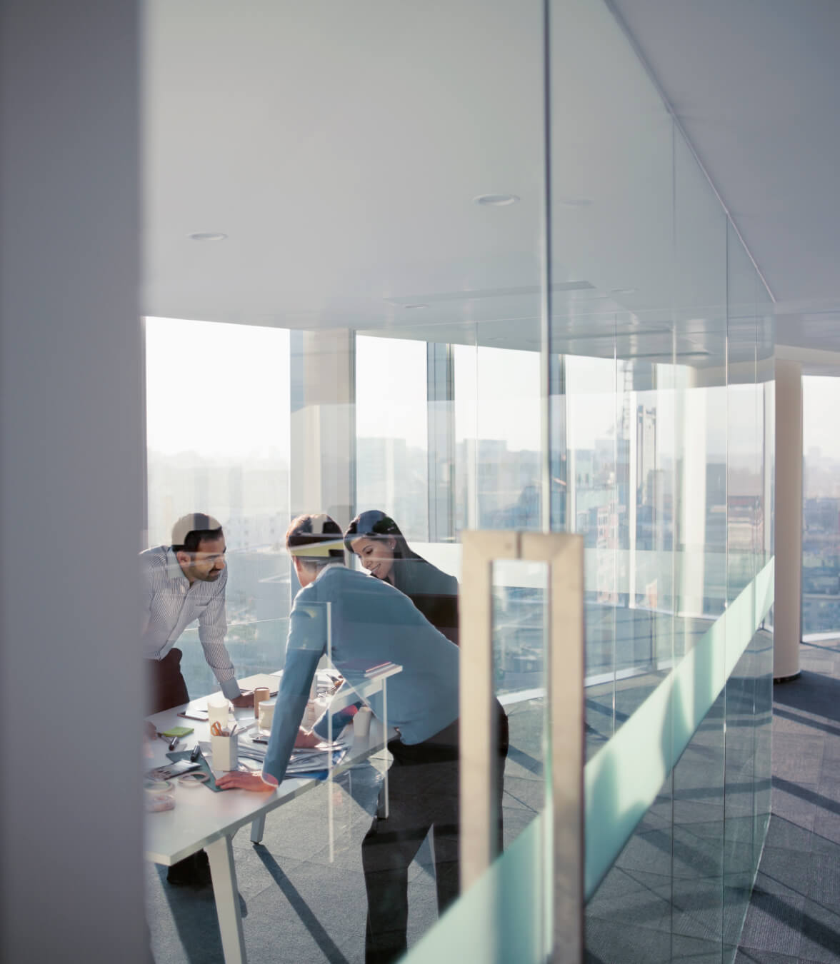 Business team gathered around a conference table in a bright office with city views.