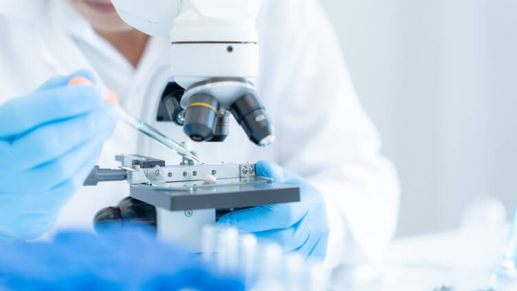professional looking through microscope