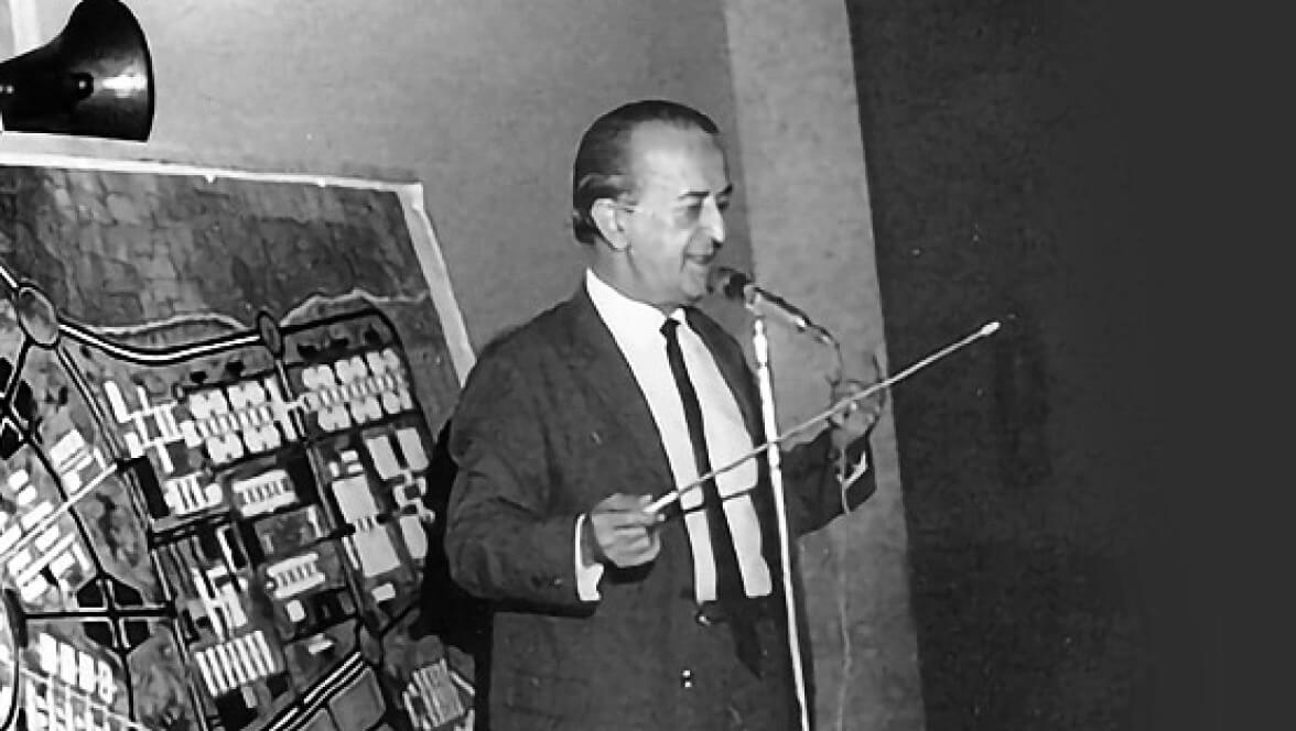 black and white photo of a person talking in front of the mic