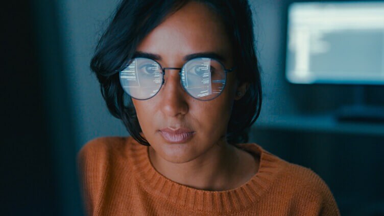 person wearing glasses working on monitors
