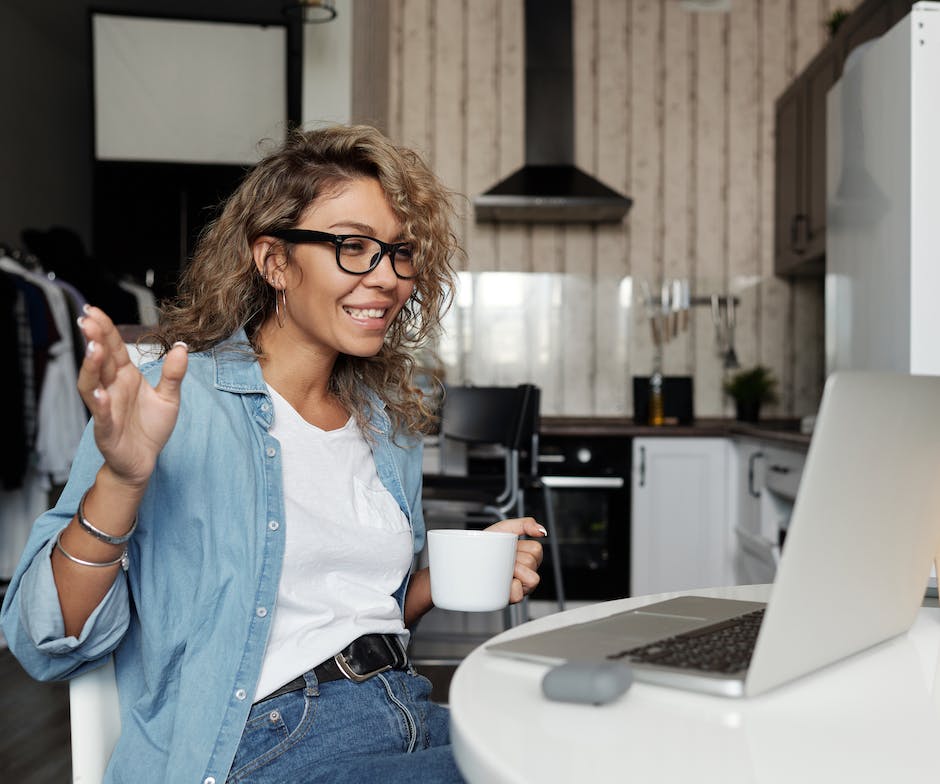 person sitting in front of laptop and talking while holding coffee