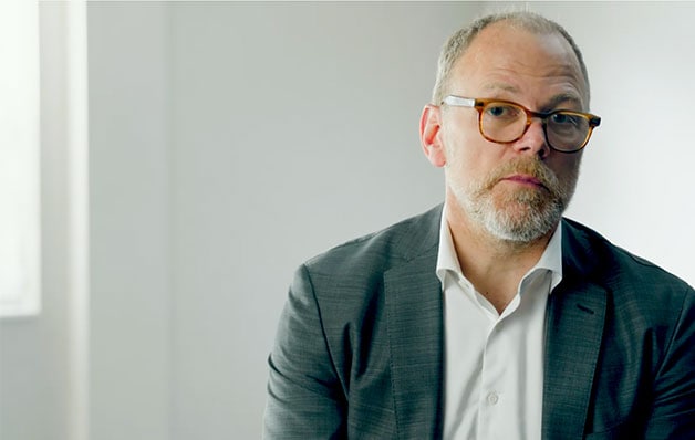 man in suit coat and glasses from the shoulders up