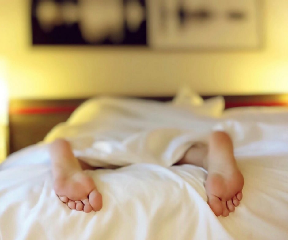 person laying in bed with feet showing