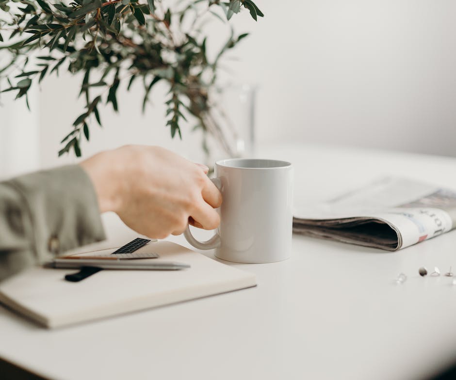 person holding coffee mug from the office desk
