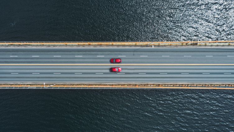 two red cars driving on highway on top of water