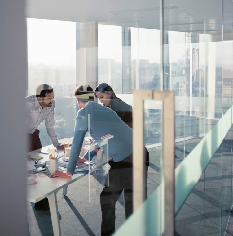 Group of 3 people reviewing documents on table in a high-rise building